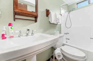 A bathroom with a white sink, toilet, and bathtub. There are toiletries on the sink, a towel rack, and a shower head. - Ski slope views, Short walk to Bear Mtn and hiking trails. Great for all seasons (Big Bear Lake)