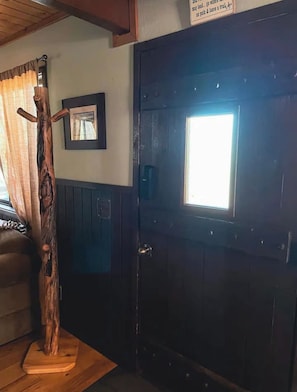 Una porta de fusta amb una finestra, un penjallabecs i un quadre encimbellat a la paret.