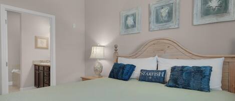 A bedroom with a bed, a nightstand, a lamp, and a dresser.