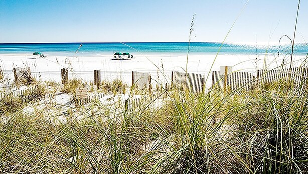 Ein Strand mit einer Holzbrüstung, Sand und blauem Himmel.