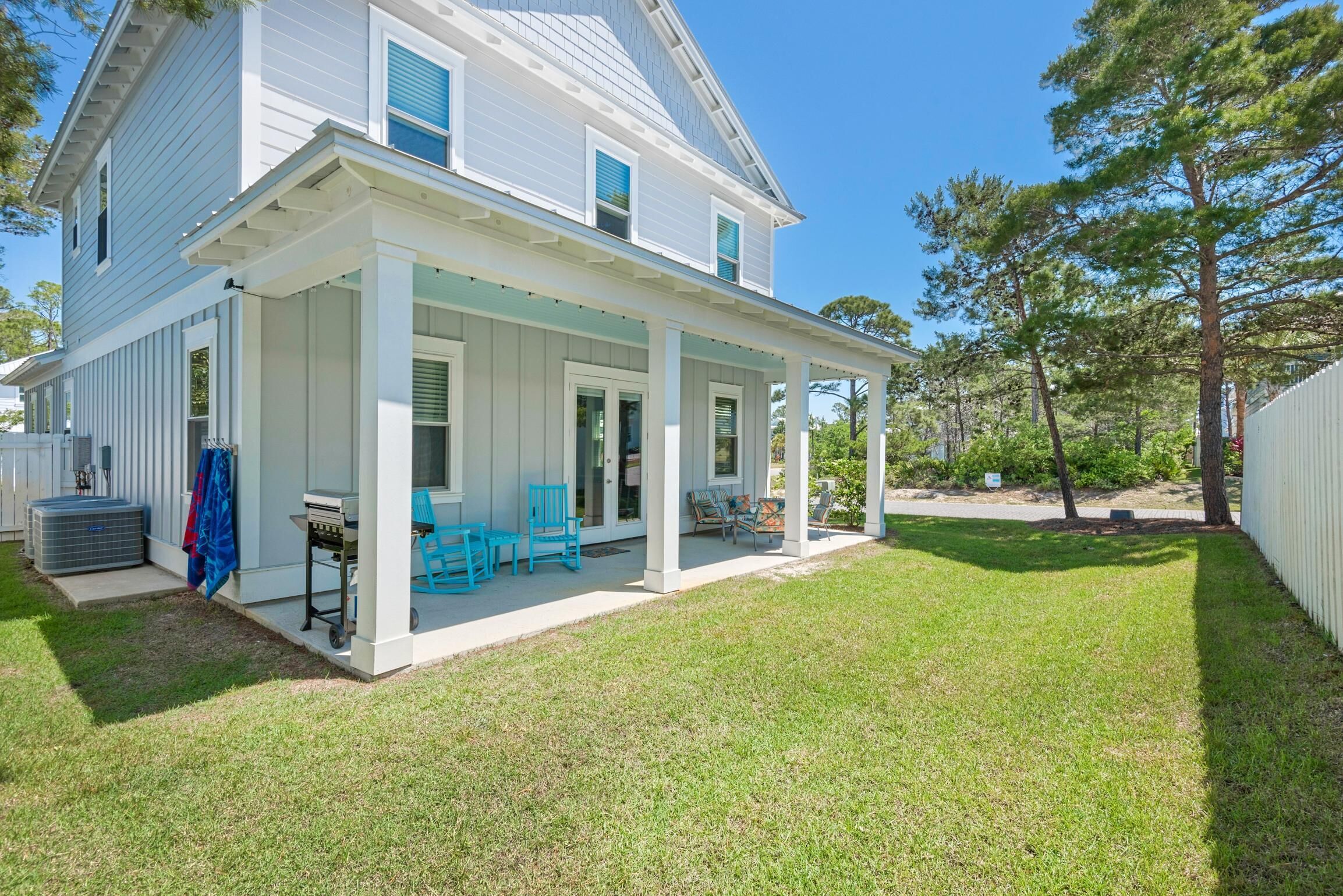 A two-story house with a covered porch, a grill, and outdoor seating.