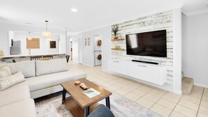 A modern living room with a sofa, coffee table, and a TV mounted on a white wall. - Summerhouse Townhomes #5 (Miramar Beach)