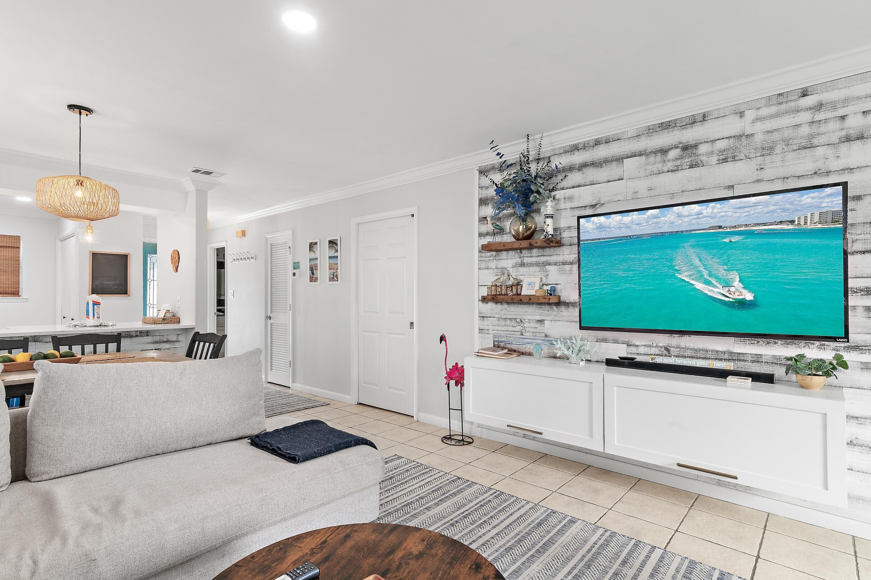 A modern living room with a large flat-screen TV, a sofa, and a dining area with a table and chairs.
