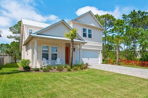 A two-story house with a covered porch, a garage, and a well-maintained lawn. - Shore Enough (Miramar Beach)