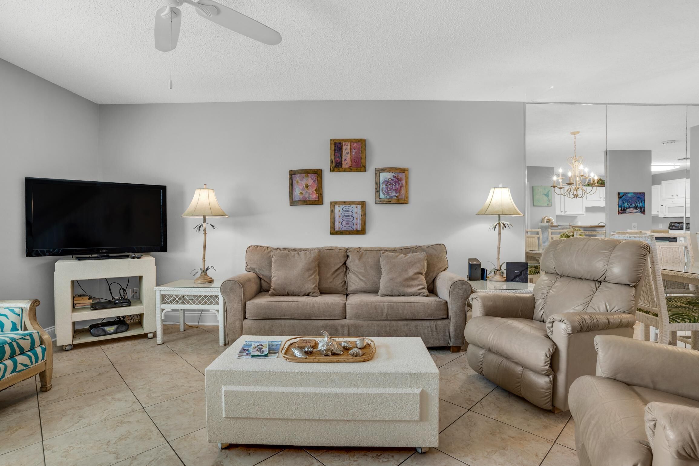A living room with a sofa, armchair, coffee table, TV, and artwork on the wall.