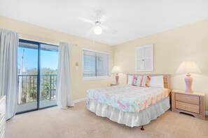 A bedroom with a large bed, two bedside tables with lamps, a ceiling fan, a sliding glass door to a balcony, and a window with blinds. - Sandprints B2- Owen's Oasis (Miramar Beach)