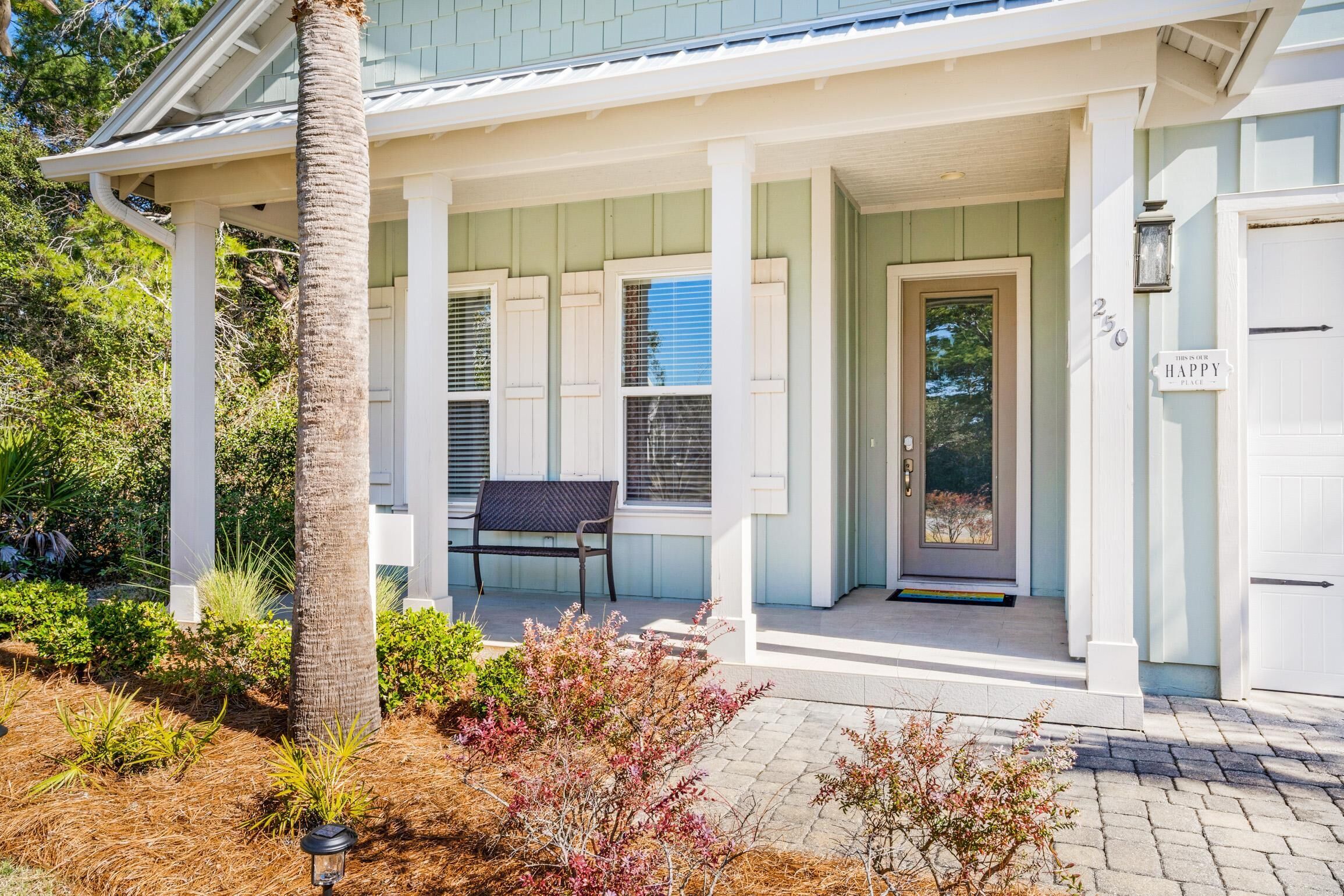 A house with a covered porch, a bench, and a door with a number sign.