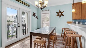 A kitchen with a tiled backsplash, wooden stools, a chandelier, and a sign reading "NEPTUNE'S NOOK". - Neptune's Nook (Miramar Beach)