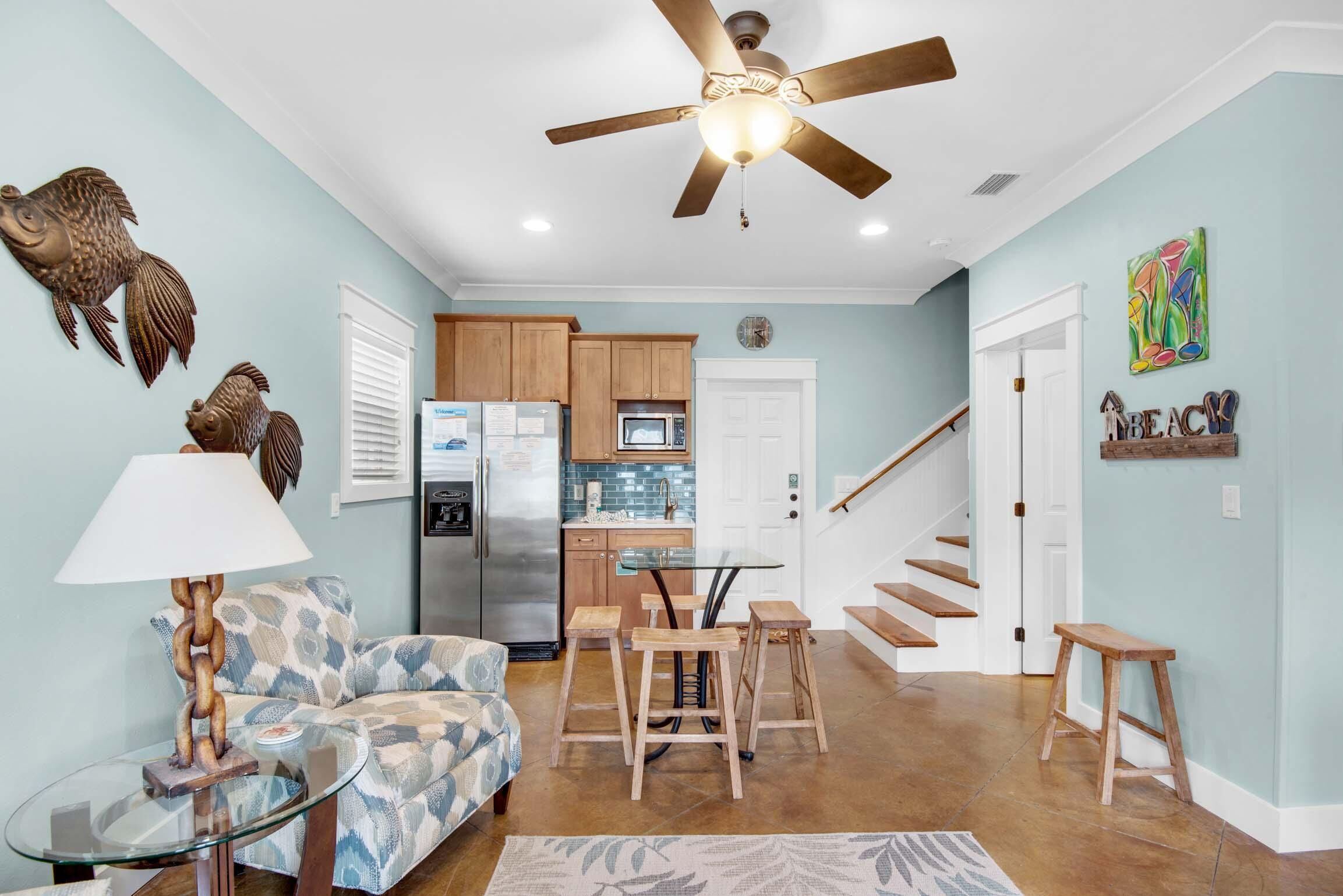 A modern living room with a sofa, glass coffee table, and a ceiling fan.