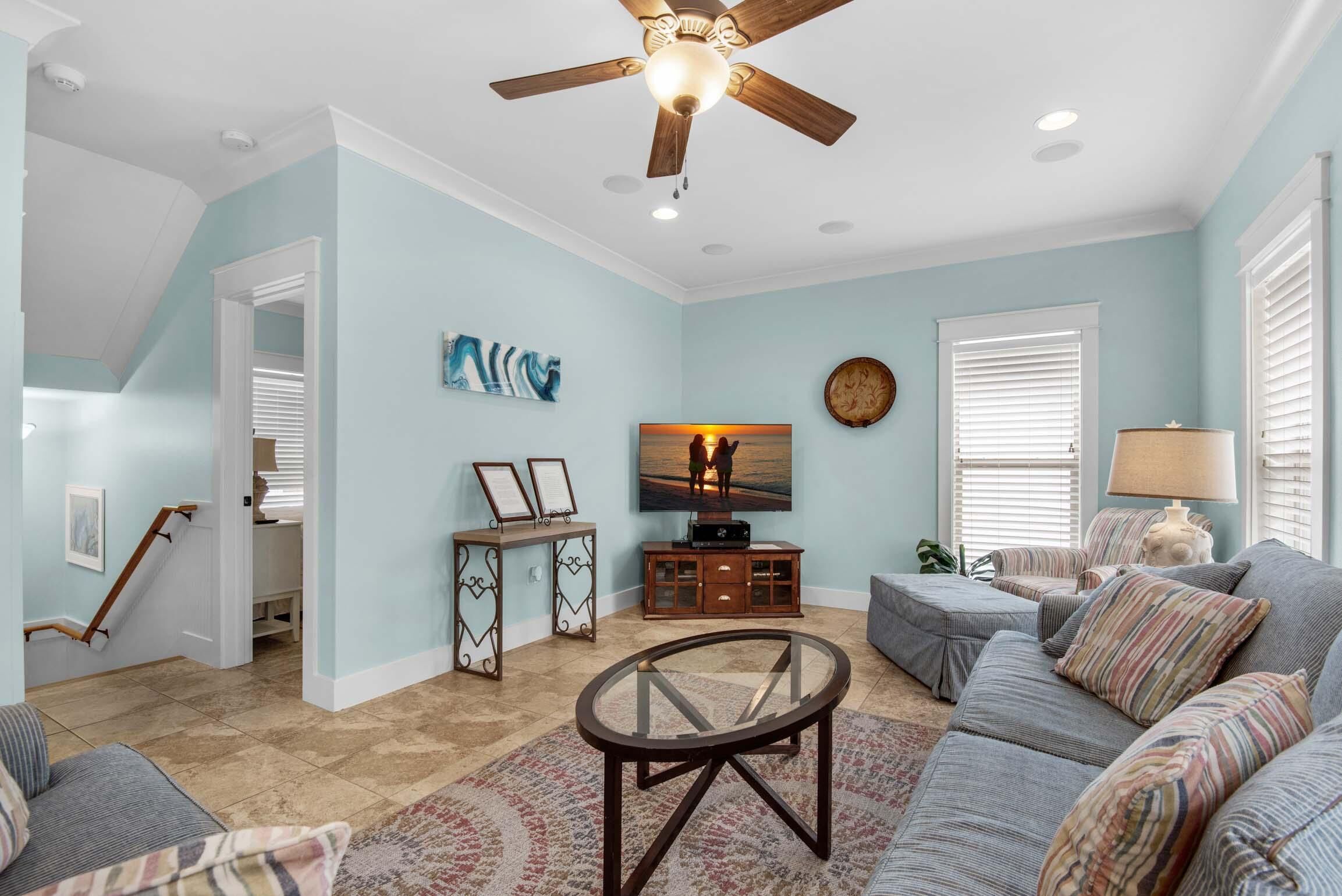 A living room with a ceiling fan, a TV, a sofa, and a coffee table.