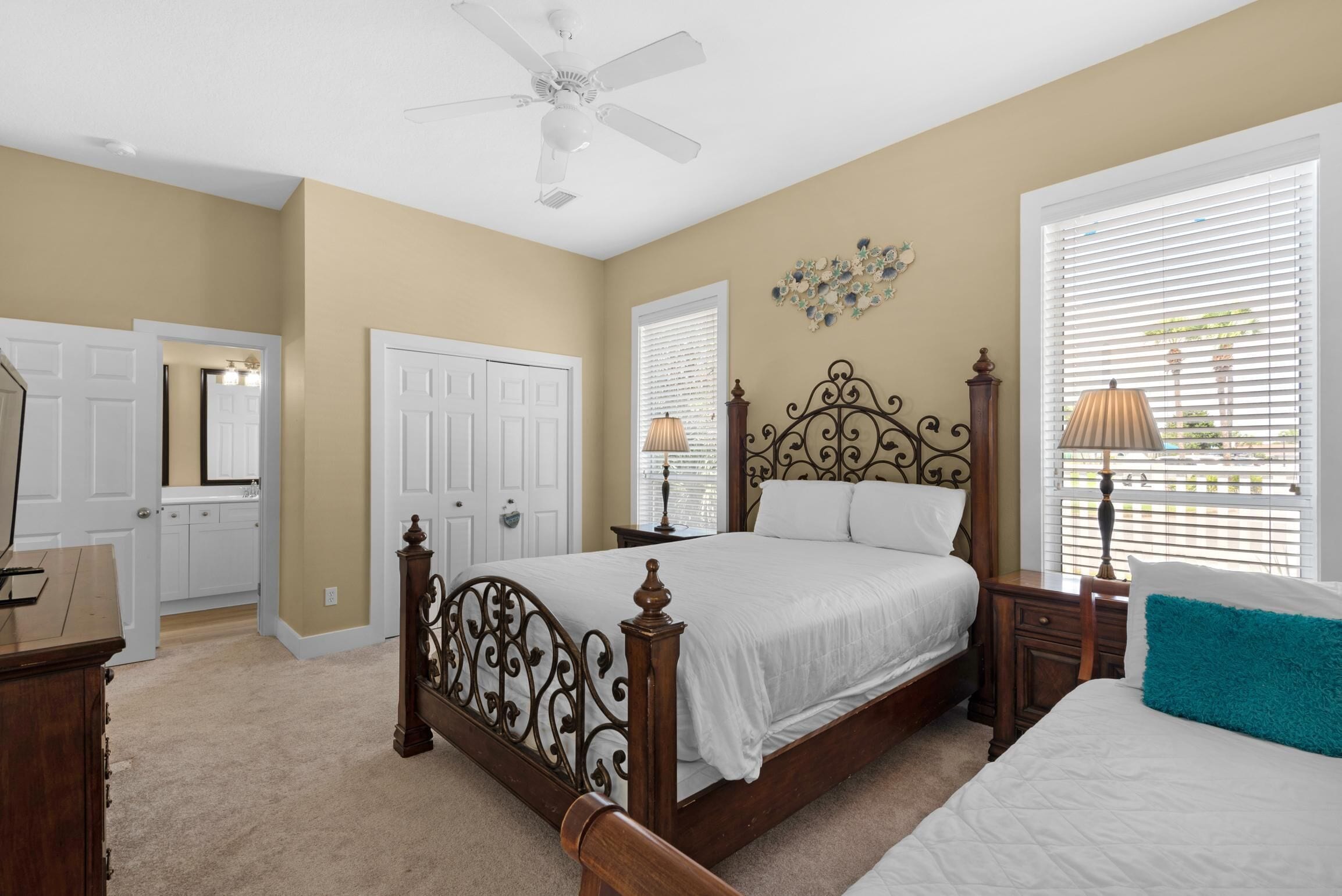 A bedroom with a wooden bed, a ceiling fan, and a window with blinds.