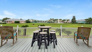 A wooden deck with a round table and four stools, overlooking a golf course. - The Crab Shack (Miramar Beach)