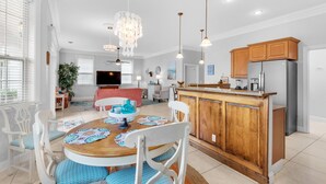 A modern kitchen with wooden cabinets, a built-in island, and pendant lighting. - The Crab Shack (Miramar Beach)