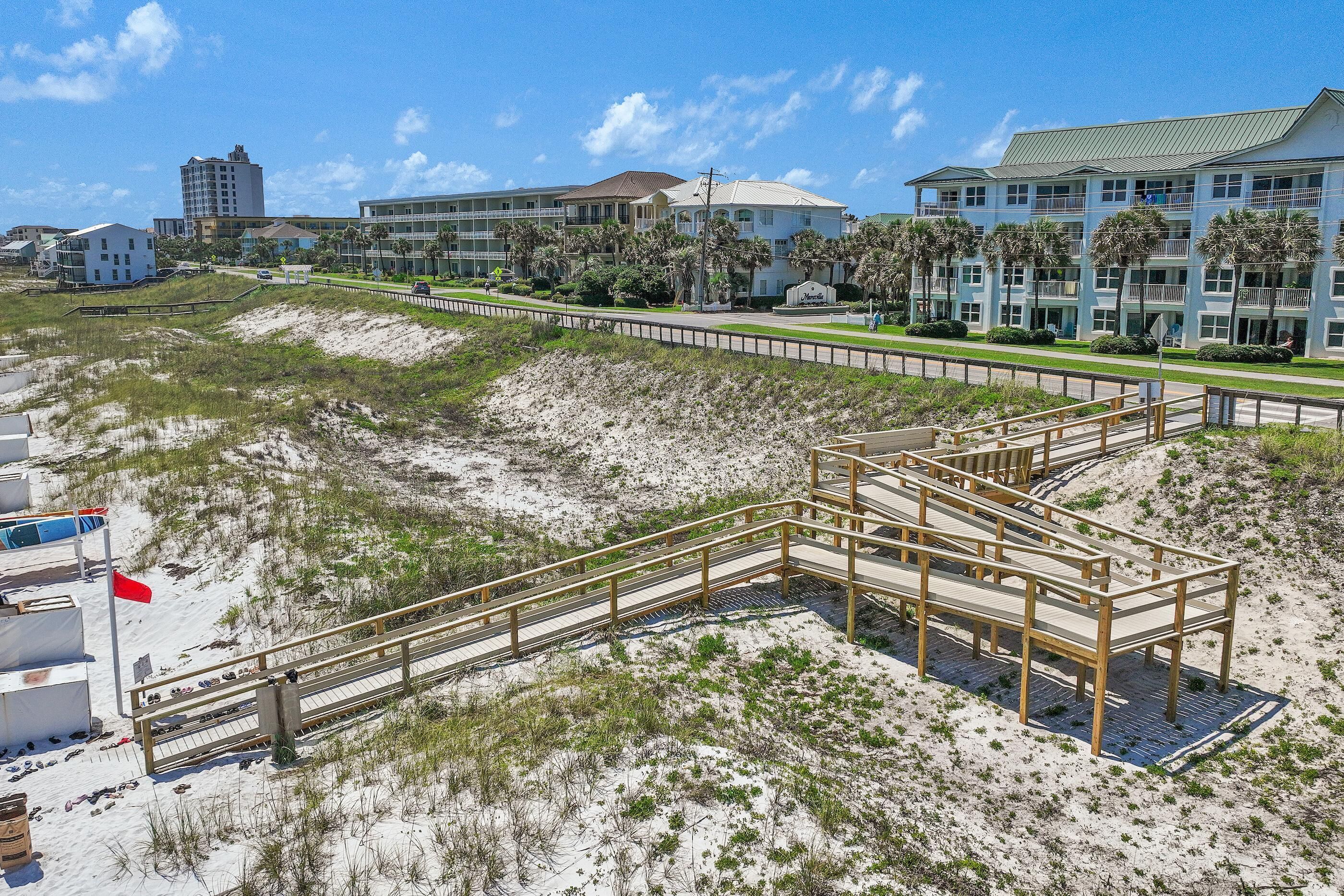 A beachfront hotel with a boardwalk, beach access, and a view of the ocean.