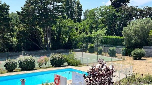 A swimming pool surrounded by greenery and a tennis court. - Apartment with pool and beach access 2*. No. 31 (Quiberon)