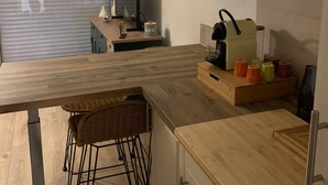 A modern kitchen with wooden countertops, a built-in stove, and a hanging light fixture. - Apartment with pool and beach access 2*. No. 31 (Quiberon)