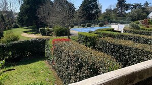 A well-maintained garden with a variety of hedges, a clear blue sky, and a fenced area in the background. - Apartment with pool and beach access 2*. No. 31 (Quiberon)