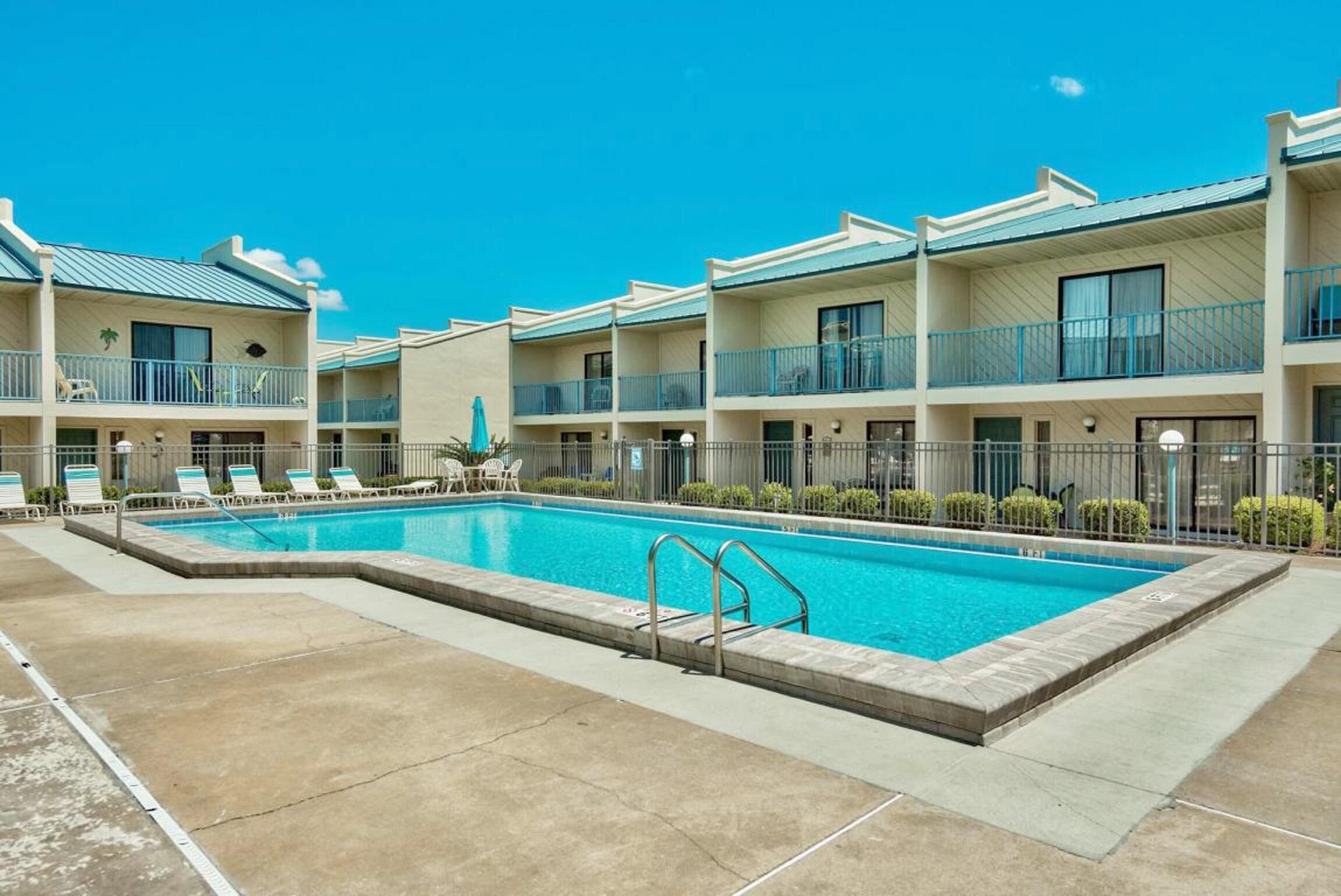 Un hôtel doté d’une piscine, de nombreux balcons et offrant une vue sur un ciel d’un bleu éclatant.