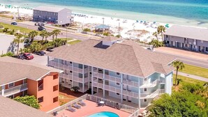 A multi-story hotel with a swimming pool, located near a beach with clear blue waters. - Gulfview I 313 (Miramar Beach)