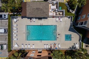 Vista aérea de una piscina en la azotea con sillones de descanso, una pequeña terraza y vegetación circundante.