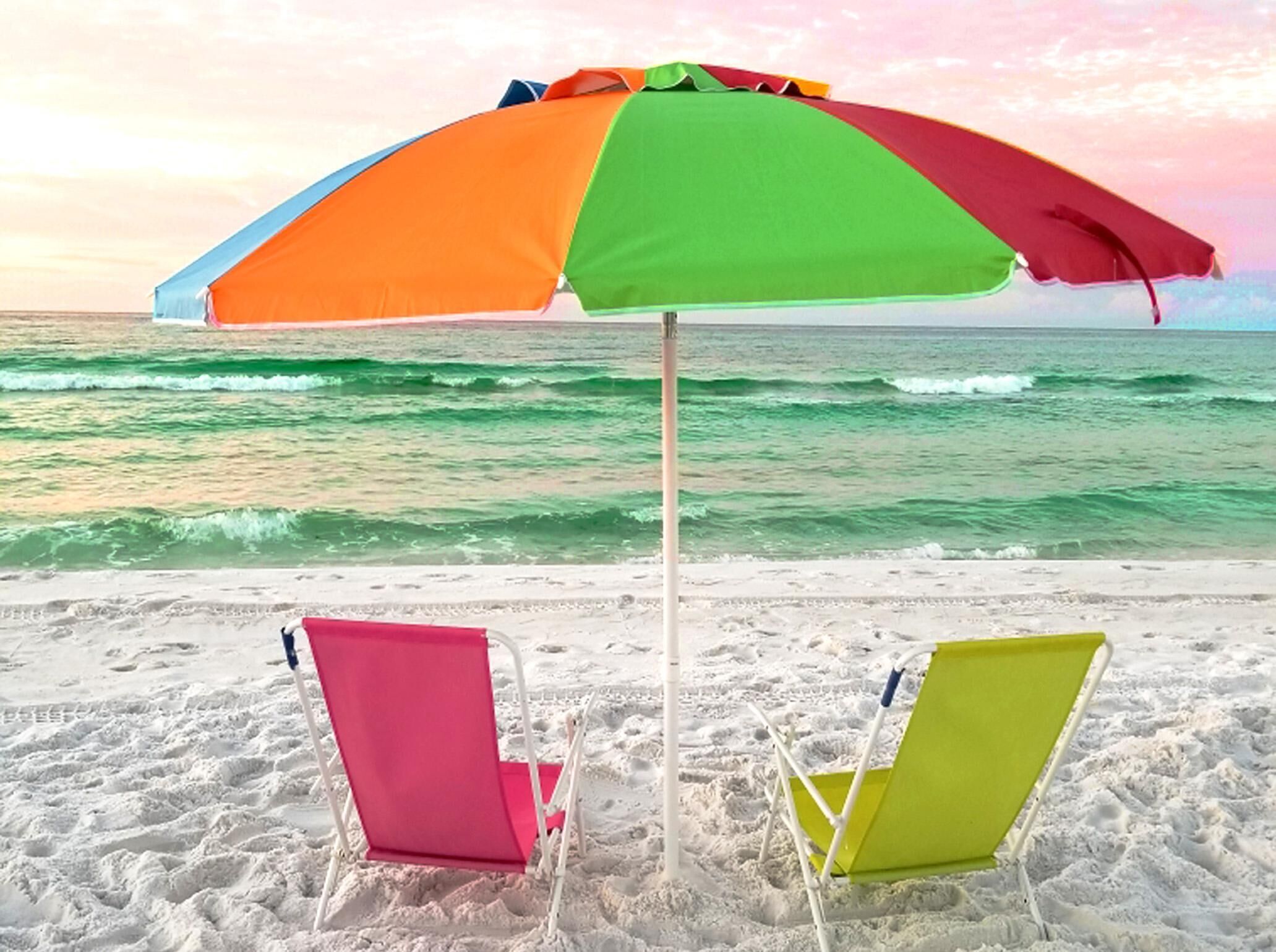 Une plage avec deux chaises de plage et un parasol coloré.