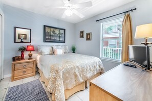 A bedroom with a bed, nightstand, lamp, TV, and window with blinds.