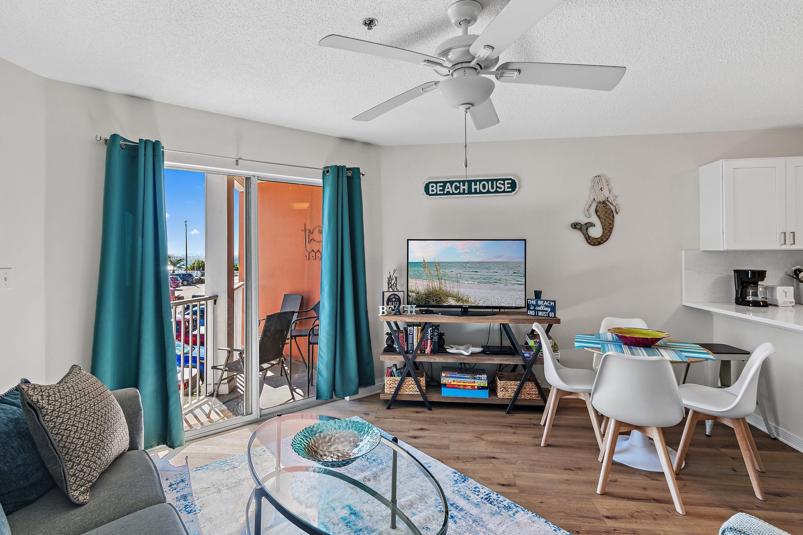 A modern living room with a TV, seating, and a balcony with curtains.