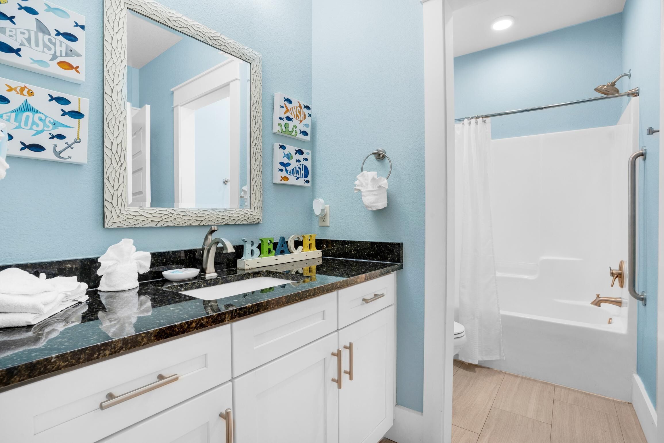 A bathroom with a sink, mirror, and shower. There are towels on the counter and a shower curtain.