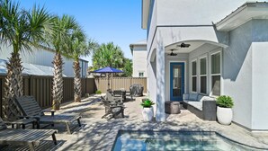 A backyard with a swimming pool, patio furniture, and a covered seating area. - Fun In The Sun (Miramar Beach)