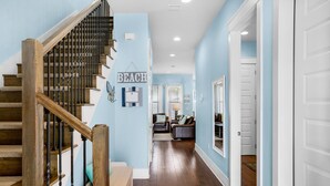 A staircase with wooden steps and black balusters, leading to a living area with a sofa and a coffee table. - Fun In The Sun (Miramar Beach)