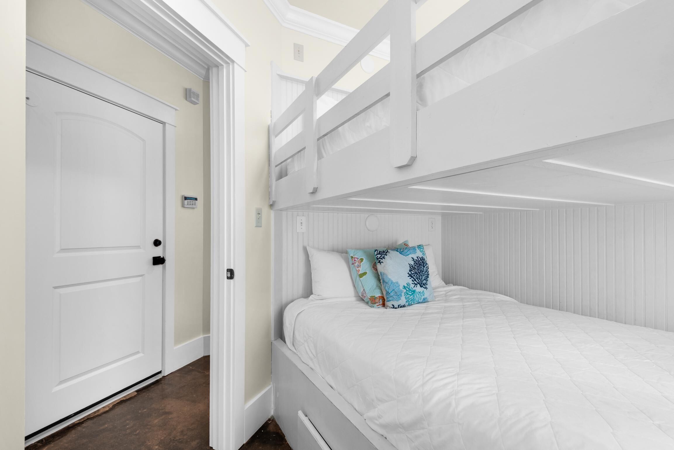 A white bunk bed with a headboard, a white door, and a small window.