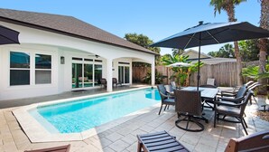 Ein Garten mit Swimmingpool, Terrassenmöbeln und einer überdachten Sitzgruppe.