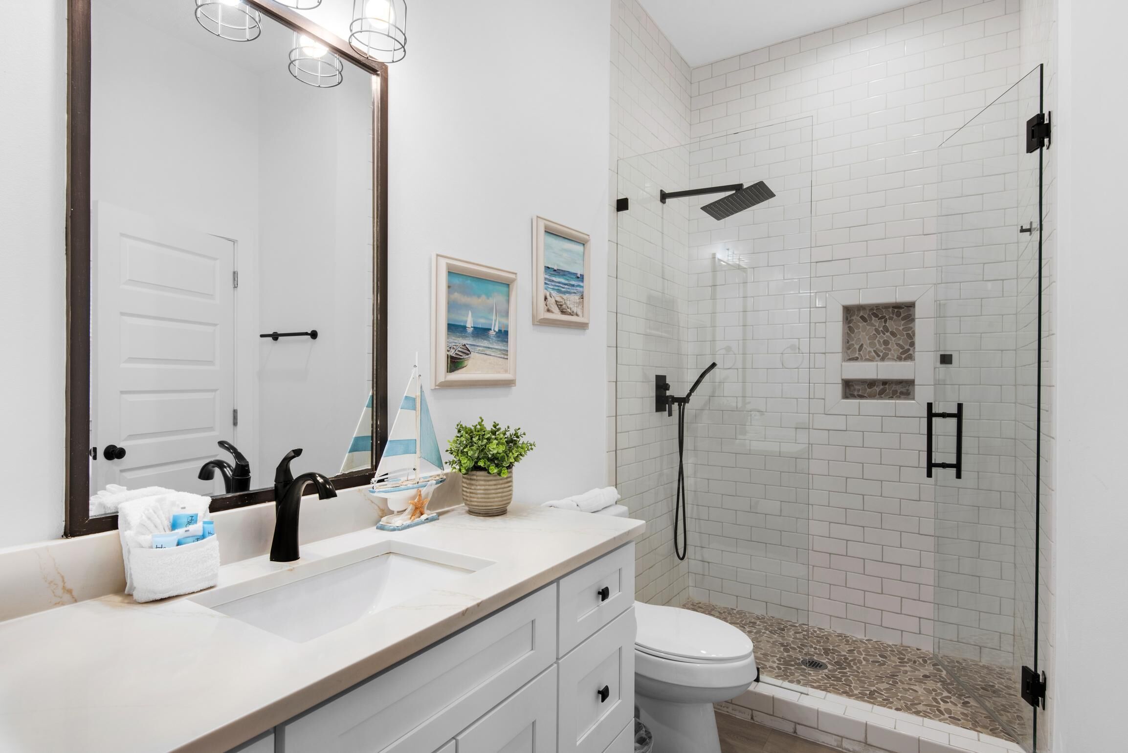 A modern bathroom with a white sink, black faucet, and a glass-enclosed shower.
