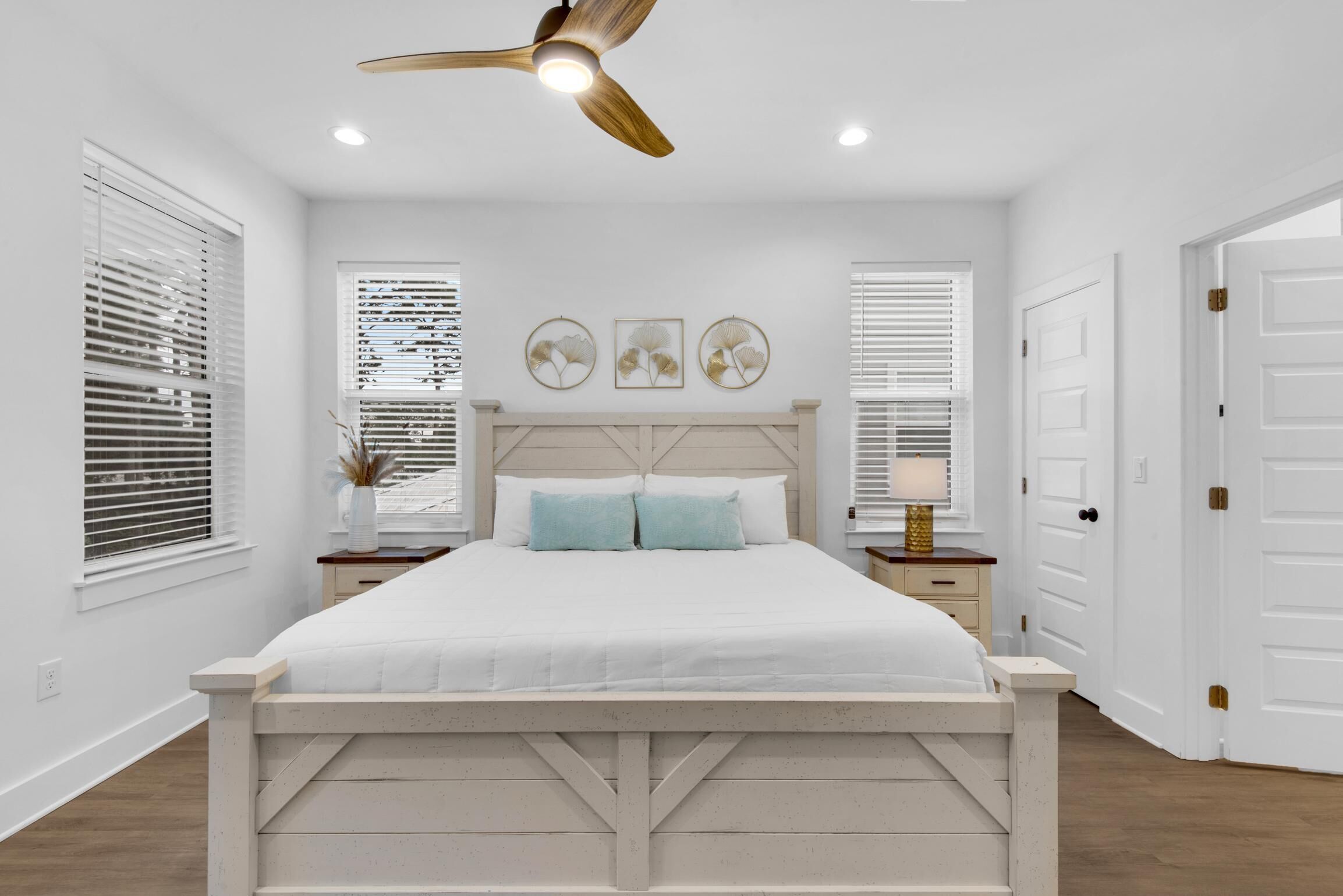 A bedroom with a bed, a ceiling fan, and two bedside tables with lamps.