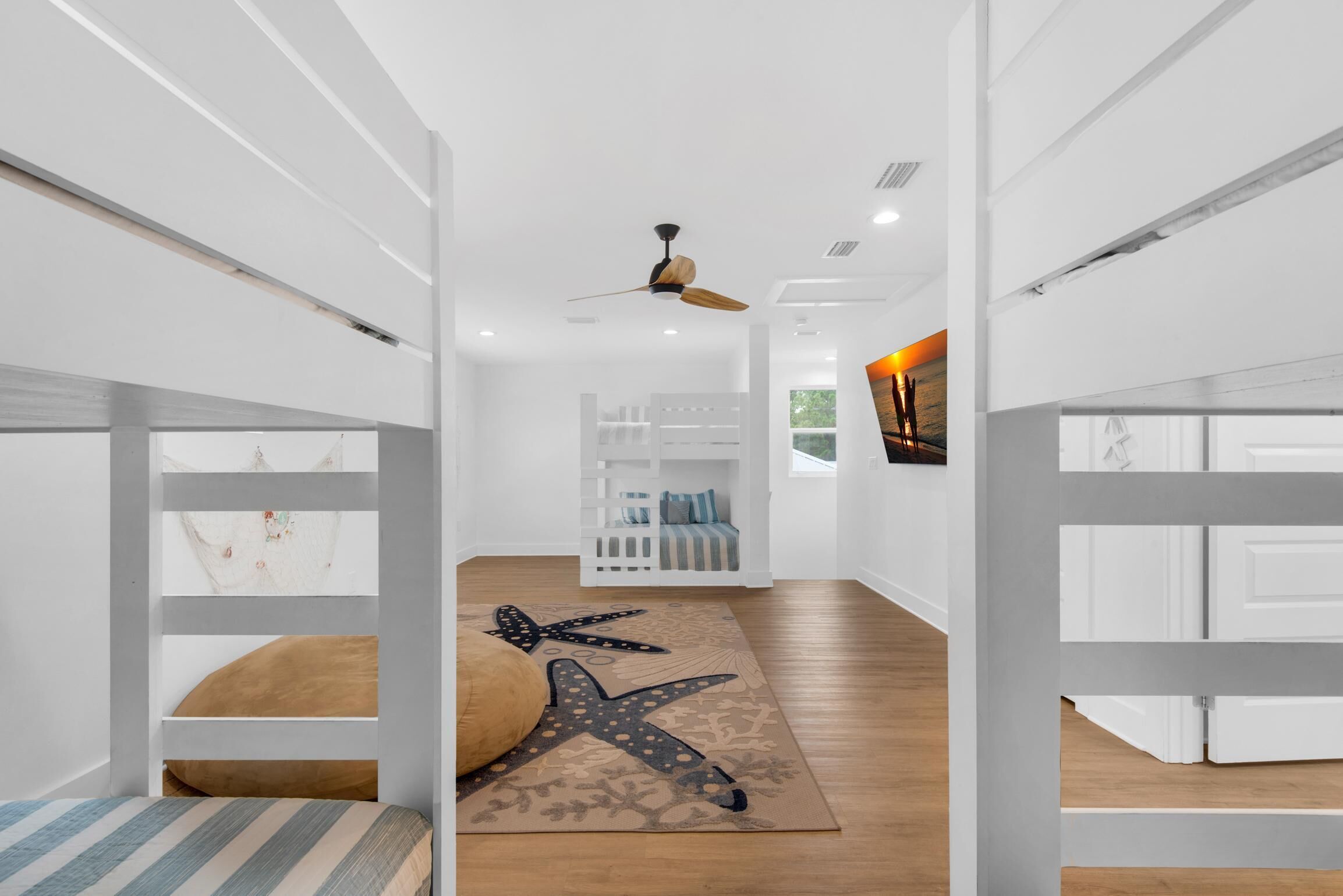 A modern interior with bunk beds, a ceiling fan, and a patterned rug.
