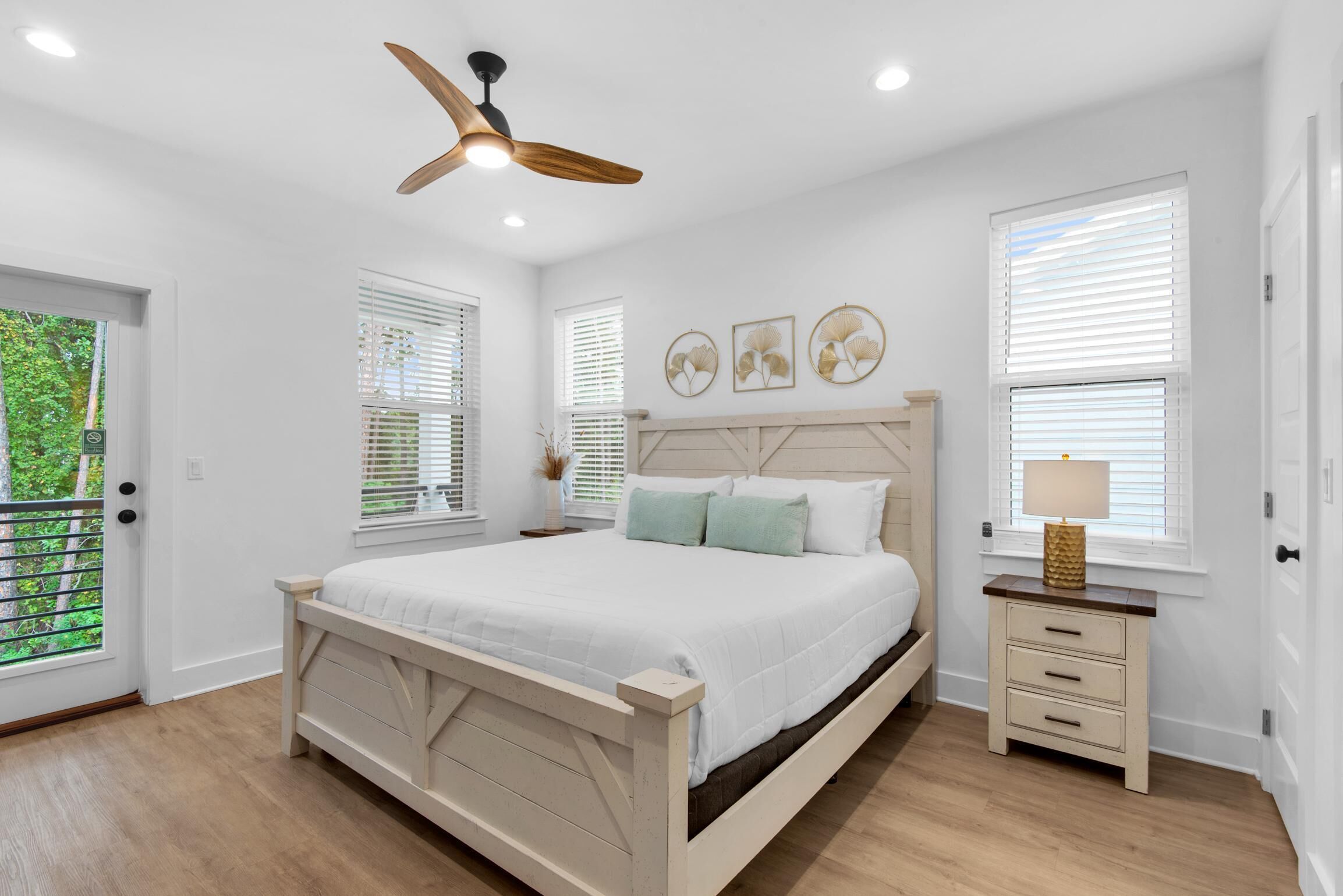 A bedroom with a wooden bed, a ceiling fan, and a nightstand with a lamp.