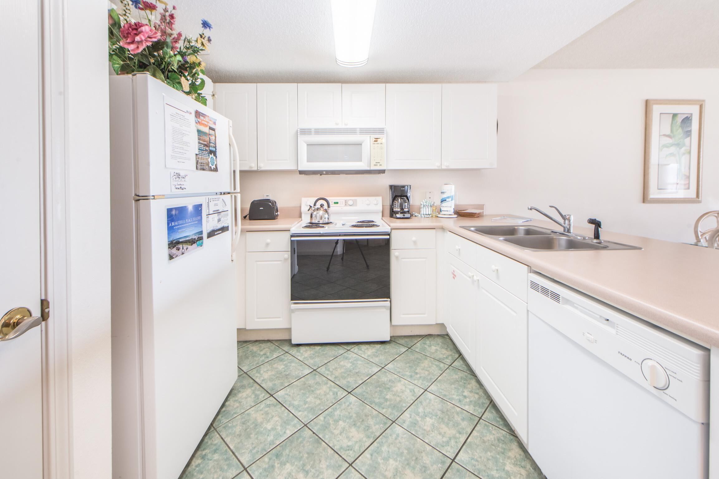 A compact kitchen with white cabinets, a microwave, a stove, a sink, and a dishwasher.