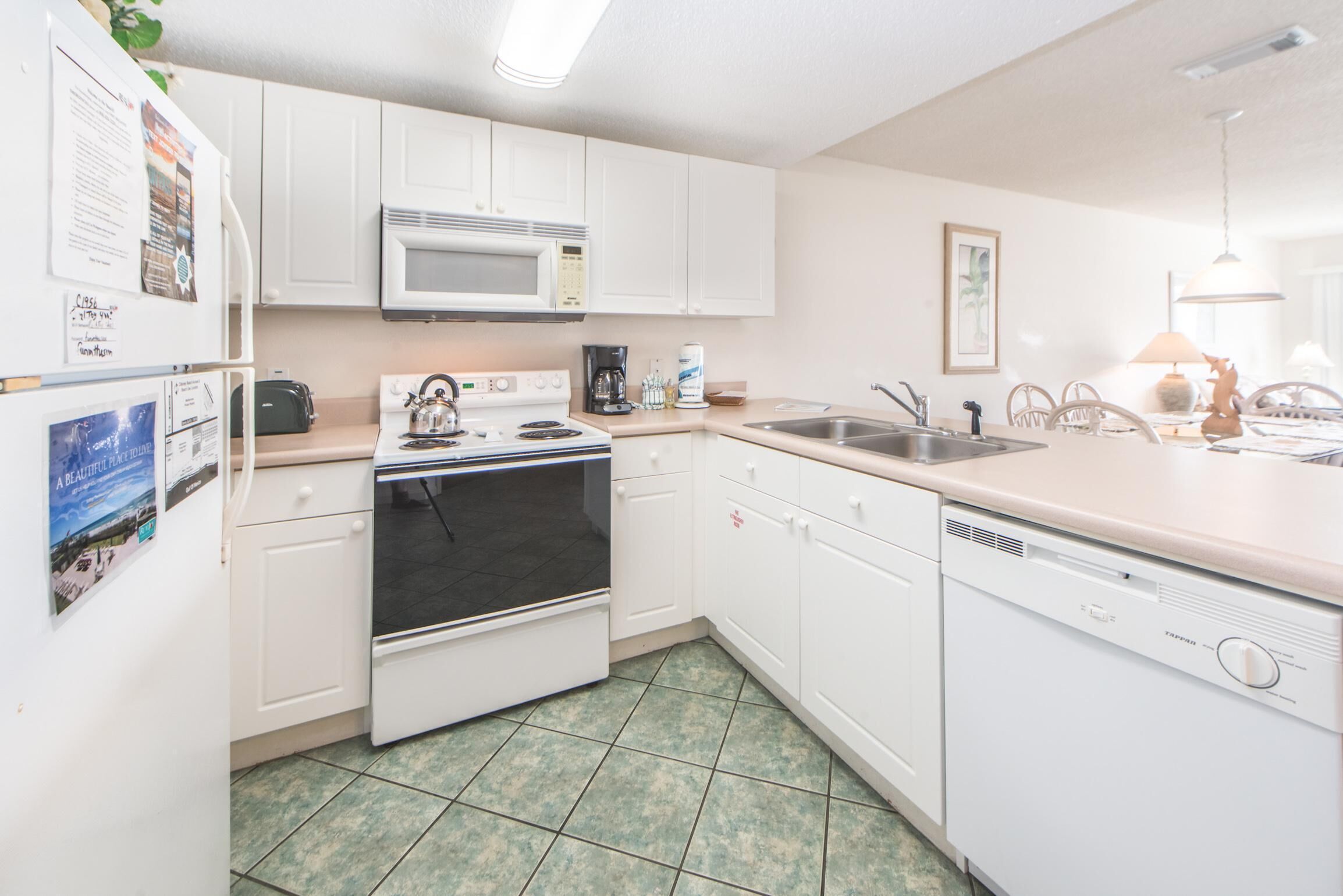 A kitchen with white cabinets, a microwave, stove, oven, dishwasher, and a sink.