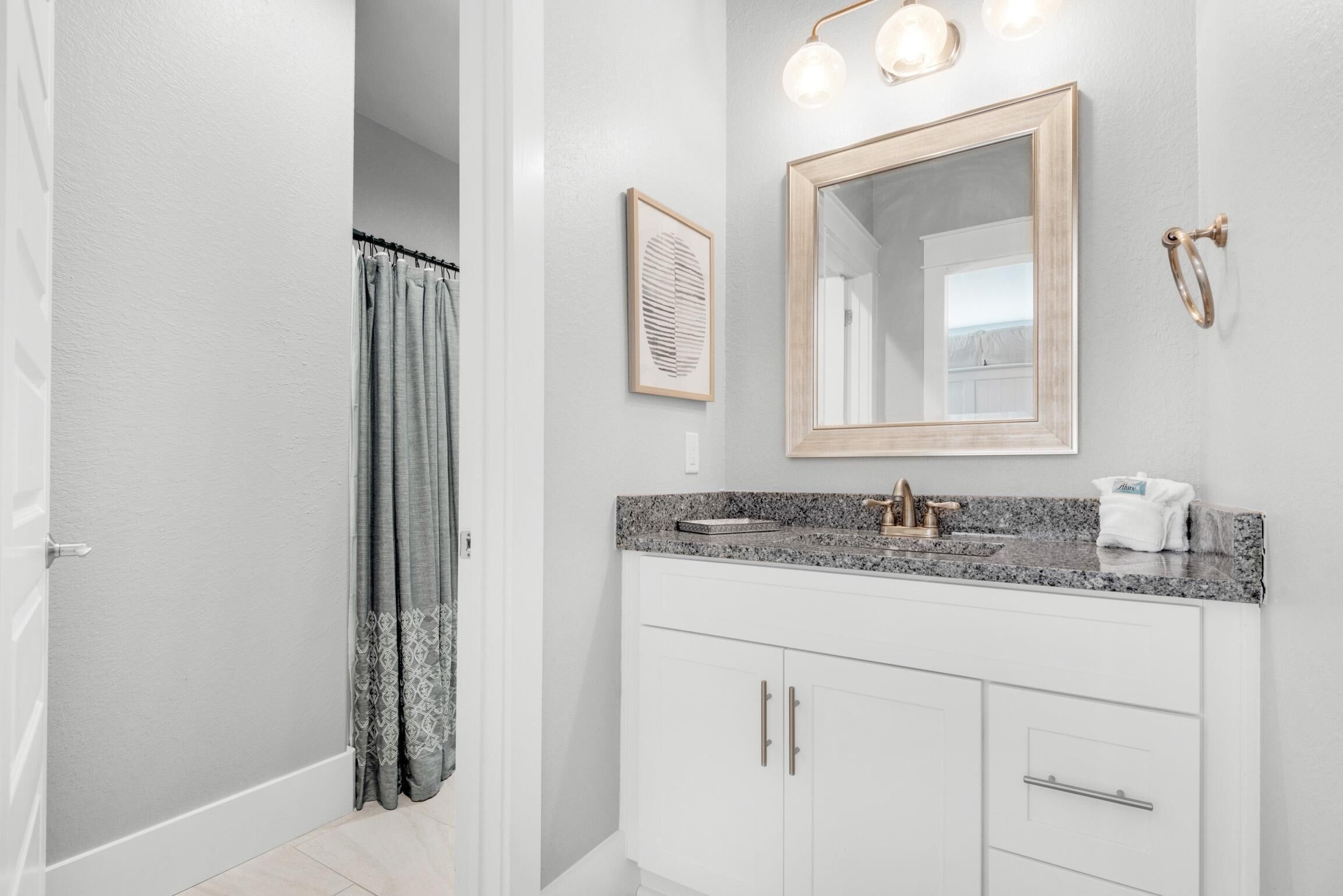 A bathroom with a white vanity, a large mirror, and a shower curtain.