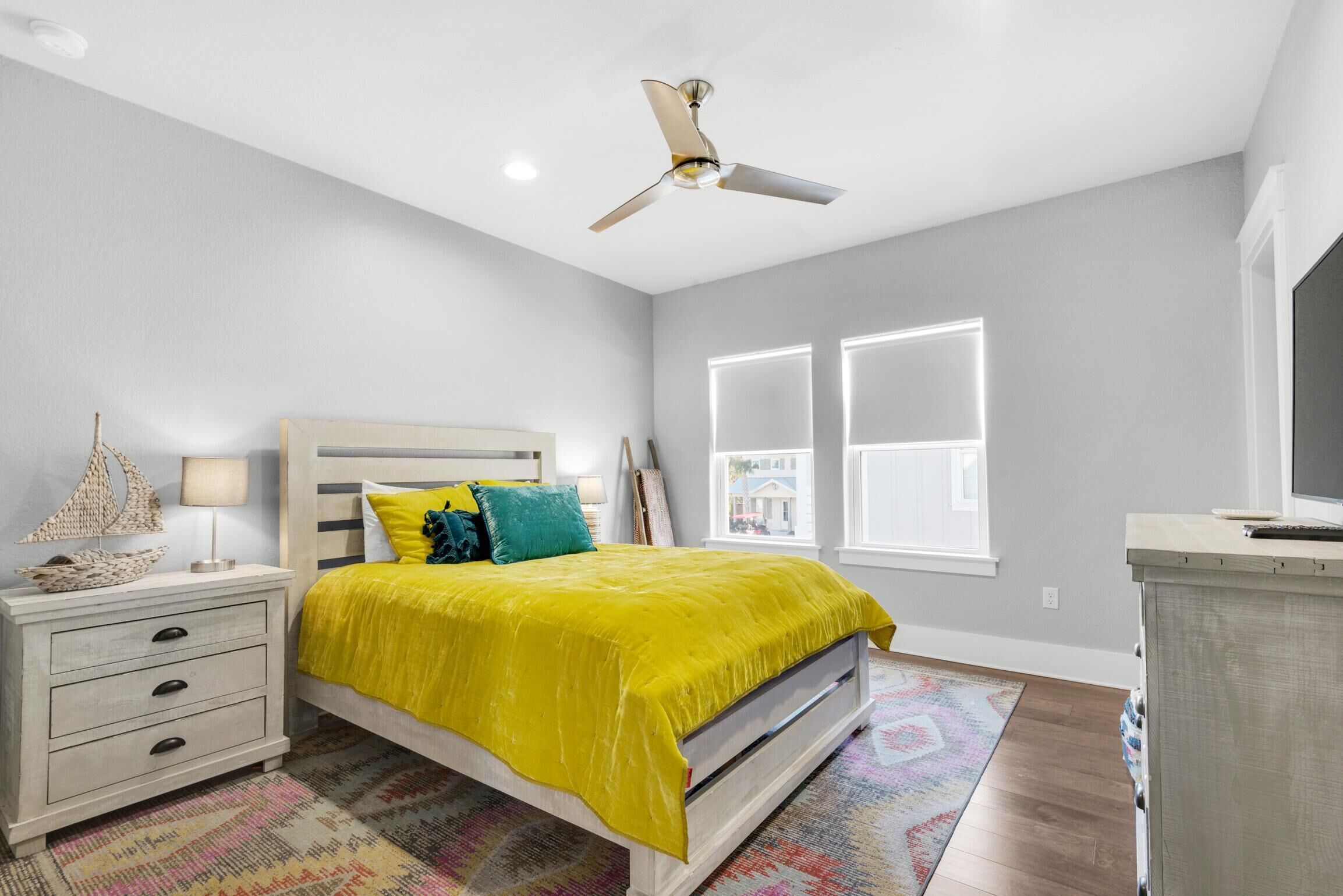 A bedroom with a bed, nightstand, lamp, and a ceiling fan.