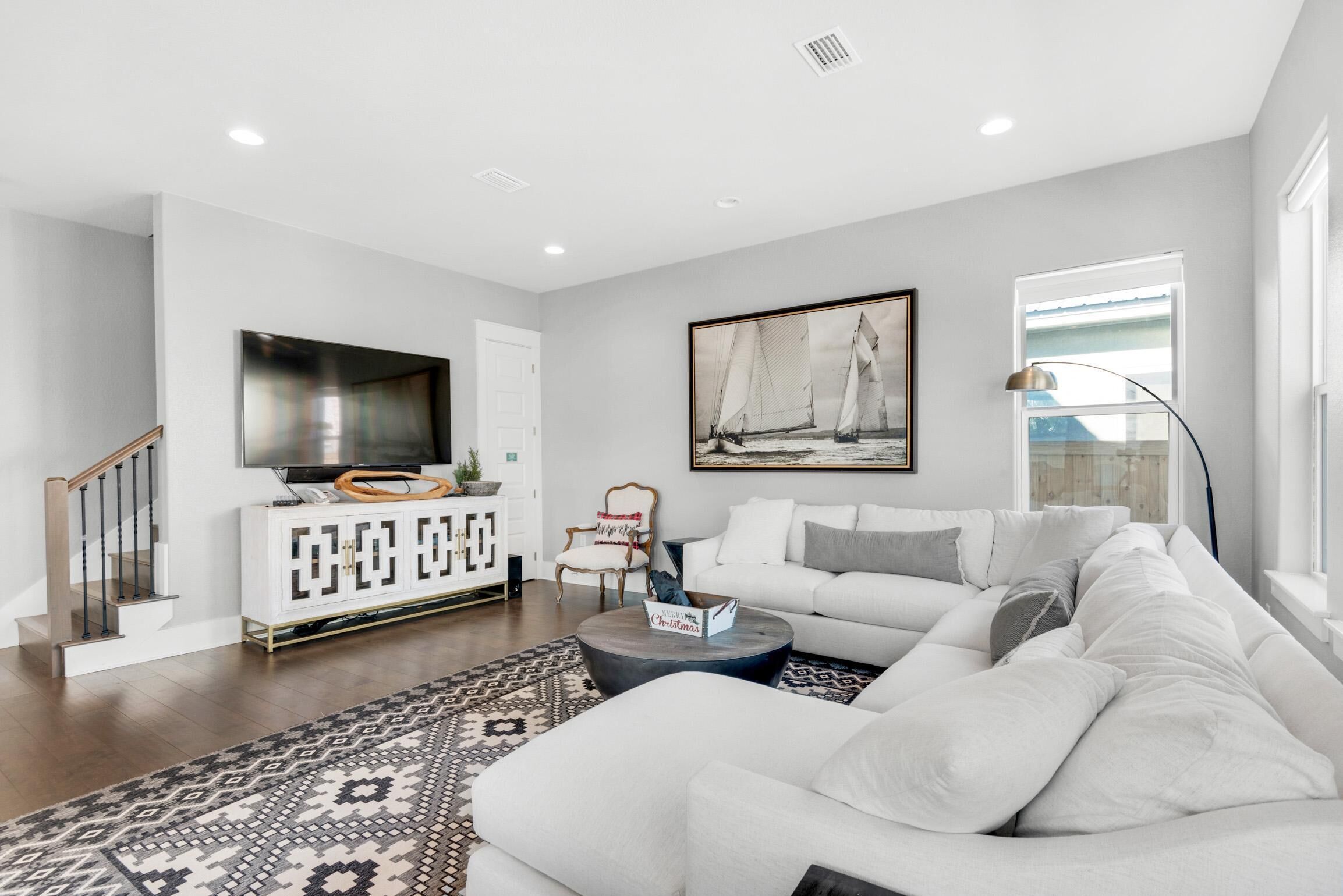 A modern living room with a white sofa, a coffee table, a TV, and a painting on the wall.