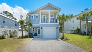 Une maison à deux étages avec un garage à l’avant, un balcon et une allée pavée.