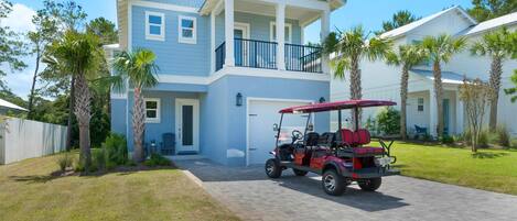 A two-story house with a covered porch and a golf cart parked in front.
