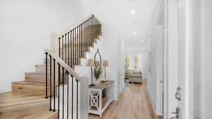 Un escalier avec des marches en bois et des rampes en métal menant à un palier où se trouvent une console et des lampes.
