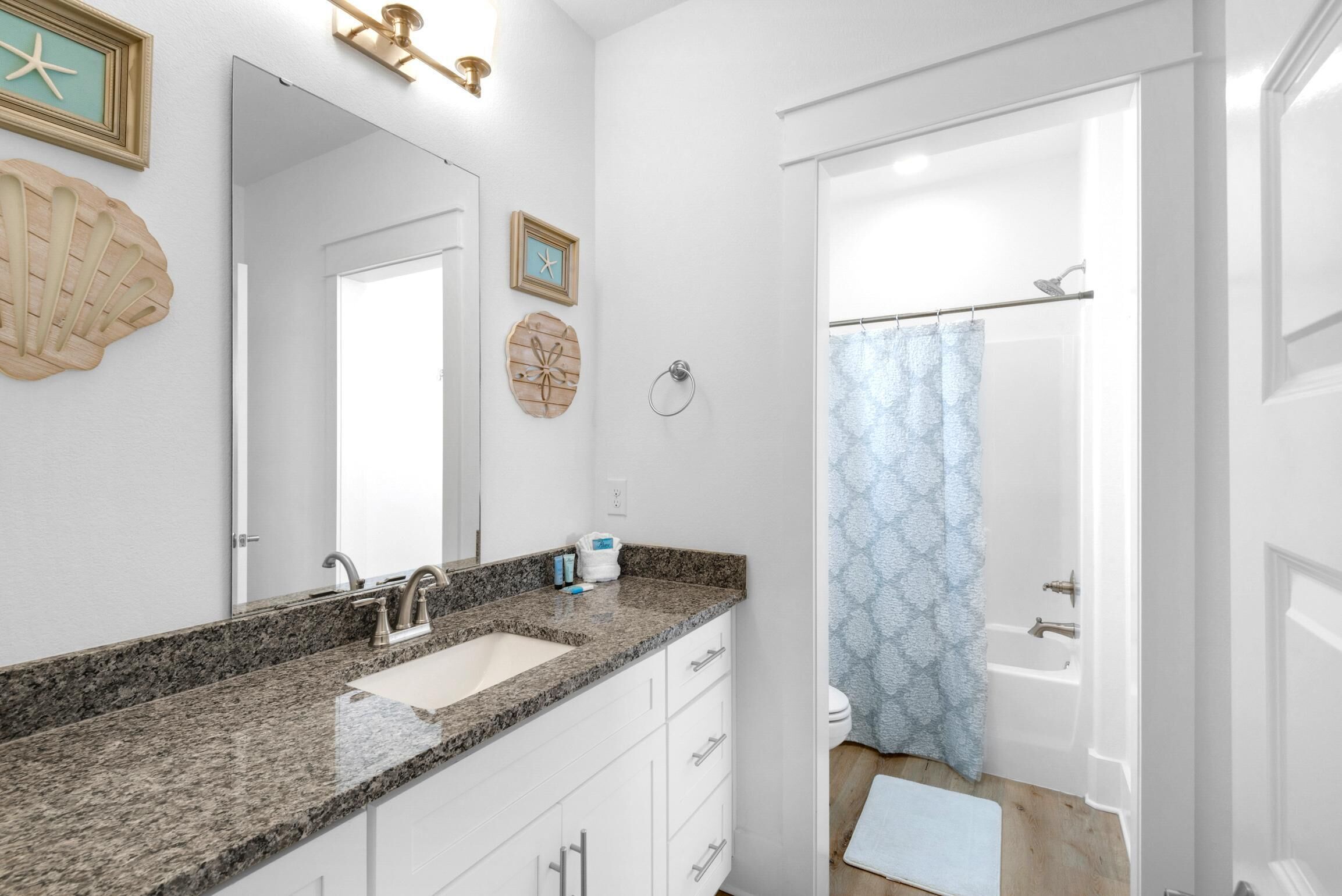 Une salle de bain avec un lavabo à vasque en granit, un miroir, un porte-serviettes et un rideau de douche.