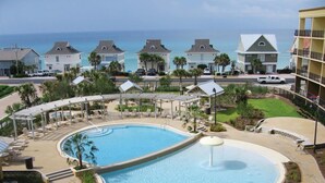 A resort with a large pool, lounge areas, and a view of the ocean. - Beach Resort 310 (Miramar Beach)