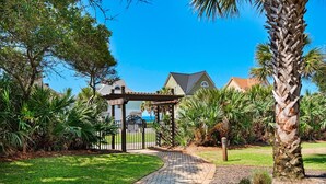 A garden pathway leading to a gazebo, surrounded by lush greenery and palm trees. - Beach Resort 310 (Miramar Beach)