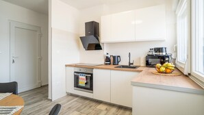 A compact kitchen with white cabinets, a built-in oven, a coffee machine, and a fruit bowl on the counter. - 1 bedroom awesome apartment in Karlobag (Karlobag)