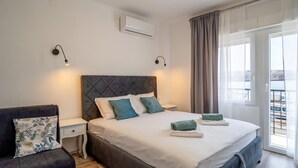 A bedroom with a bed, nightstands, a sofa, and a balcony with a view. - 1 bedroom awesome apartment in Karlobag (Karlobag)