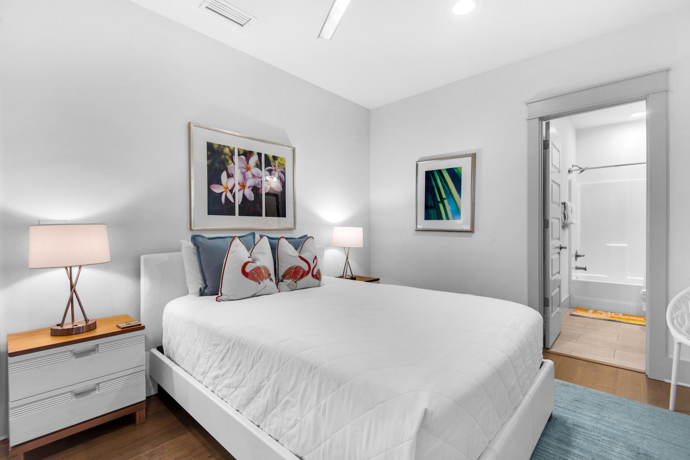 A bedroom with a large bed, two bedside tables, a nightstand, and a door leading to a bathroom.
